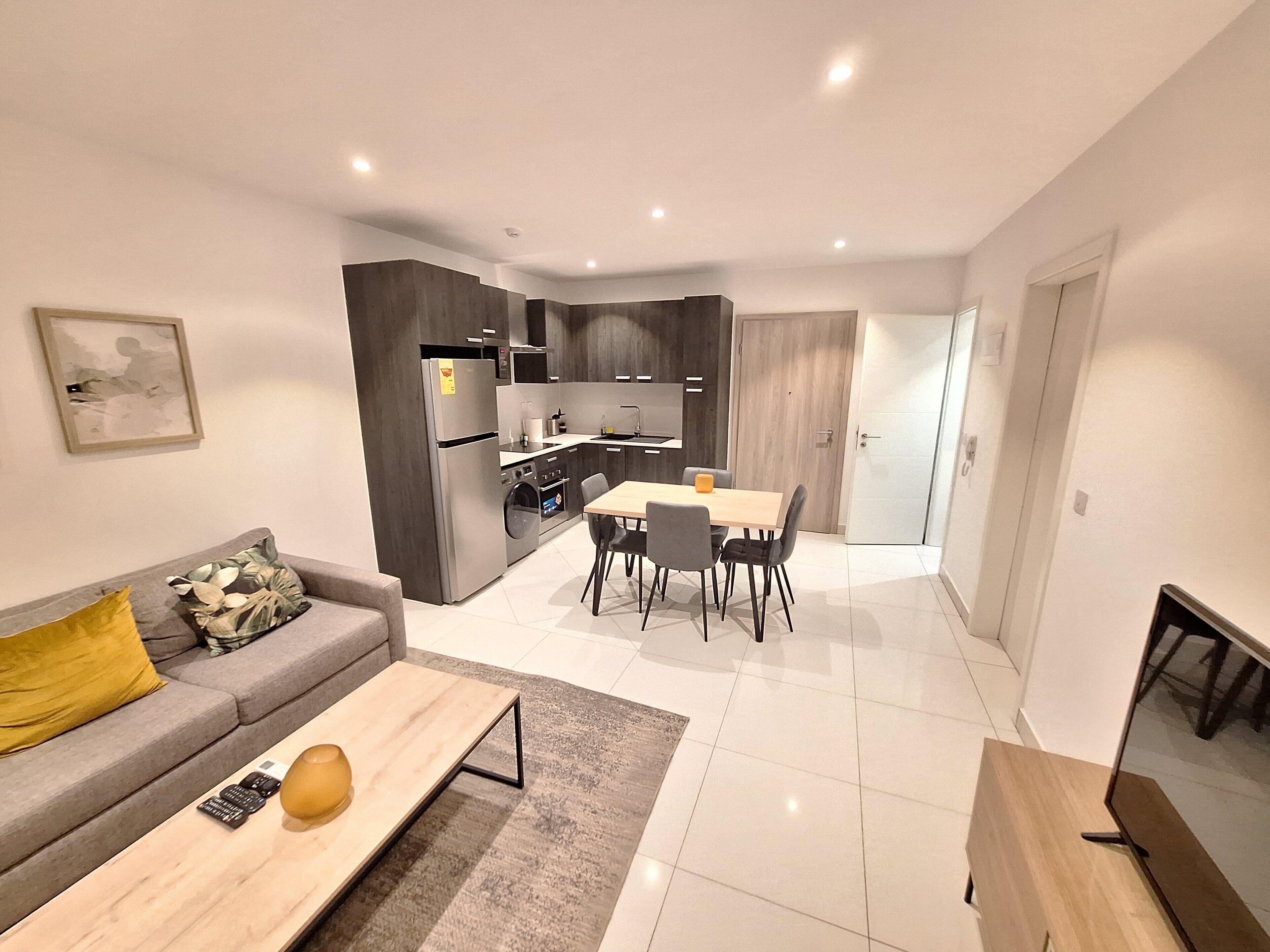 A modern apartment with a kitchen, dining area, and living room.