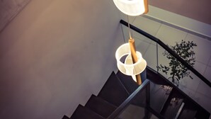 A modern staircase with a glass railing and a unique, illuminated pendant light fixture. - The Lennox Abode (Accra)