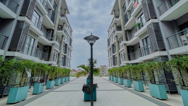Een modern appartementencomplex met een centrale looppad, plantenbakken en een lantaarnpaal.