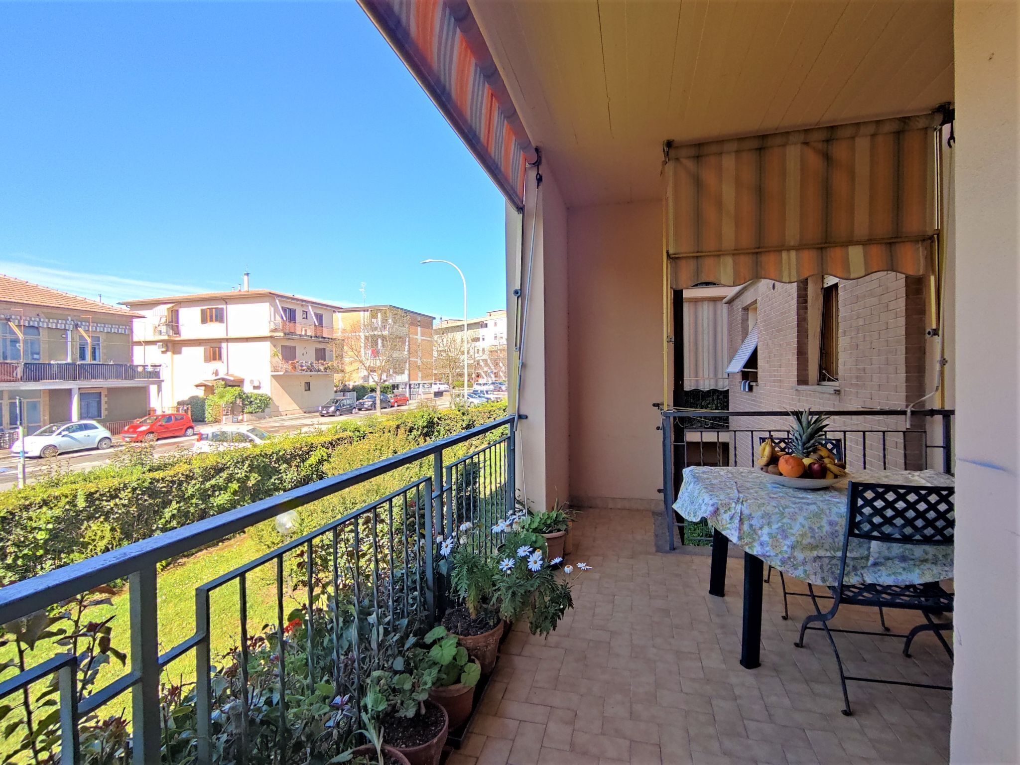 A balcony with a table, chairs, and potted plants.