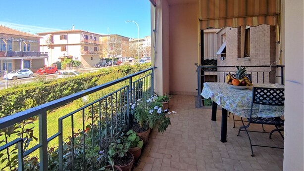 En balkon med et bord, stole og plantekrukker.