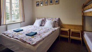 A bedroom with a bed, a window with curtains, a wooden bench, and a bunk bed. - Harrachov 141 by Interhome (Harrachov)