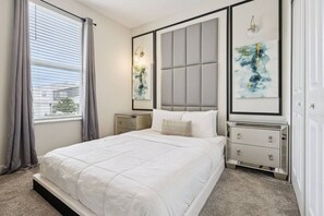 Une chambre à coucher avec un lit, des tables de chevet, une tête de lit et des œuvres d’art accrochées aux murs.