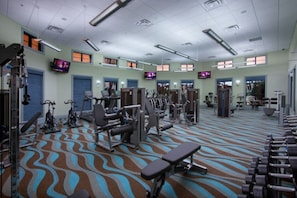 A gym with various exercise equipment, including treadmills and weight machines, and a patterned carpet.