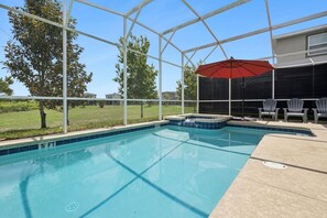A swimming pool with a hot tub, surrounded by a covered area with chairs. - Four Corners Luxury Home With Water Park And Bbq (Davenport)