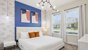 A modern hotel room with a large bed, a nightstand, a lamp, and a window with curtains.