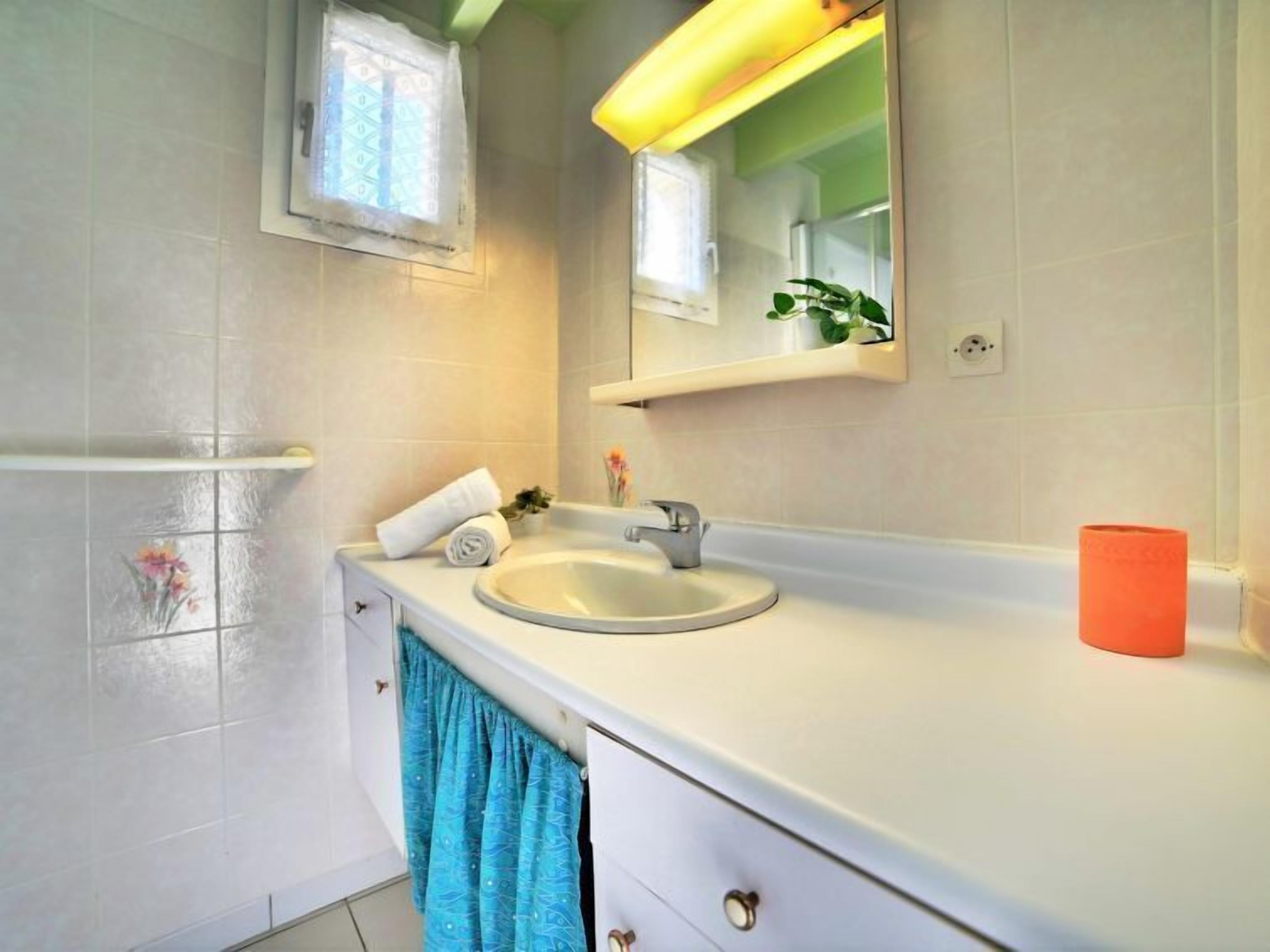 A bathroom with a white sink, a mirror, a towel, and a blue towel hanging on a rack.