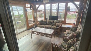 Un vaste espace de vie doté d’un plancher en bois, d’une table basse en verre, de canapés à motifs floraux et d’un téléviseur.