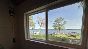 Une pièce dotée d’une grande fenêtre donnant sur un lac, d’une pagaie en bois et d’une moustiquaire.