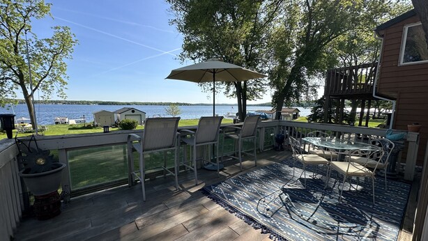 Une terrasse dotée de mobilier d’extérieur, offrant une vue sur un lac et s’ouvrant sur un ciel dégagé.