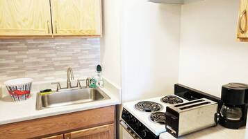 A kitchen with wooden cabinets, a stainless steel sink, a stove, and a toaster.