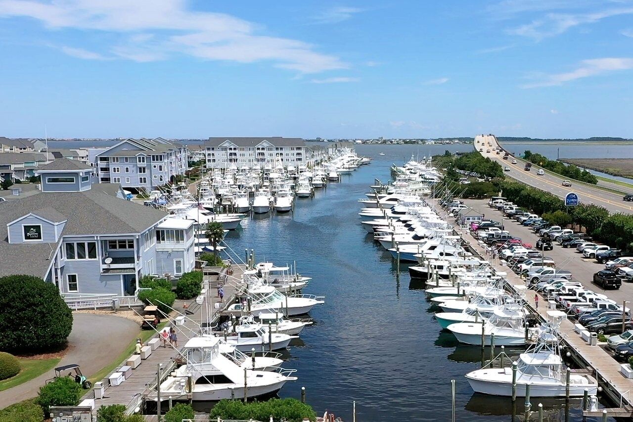 Un port de plaisance où de nombreux bateaux sont amarrés le long d’un canal étroit, entouré d’immeubles résidentiels et d’une route où circulent des véhicules.