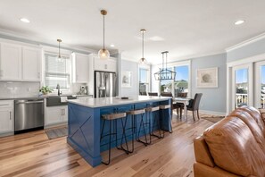 Une cuisine moderne avec des meubles blancs, un îlot central bleu et des tabourets de bar.