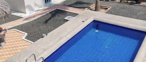 A rectangular swimming pool with a concrete edge and a metal ladder on one side.