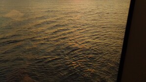 A sunset over a body of water, viewed through a window with a visible reflection. - Cabañas Vistamar  (Crucita)