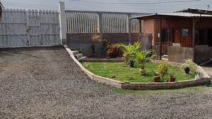 A residential property with a fenced yard, a small garden with potted plants, and a wooden building with a sloped roof. - Cabañas Vistamar  (Crucita)