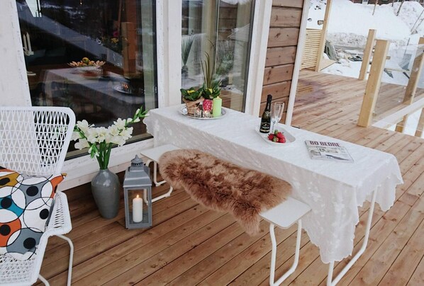 Relax in this serene outdoor seating area, complete with a table for two, a bottle of champagne, and a menu.