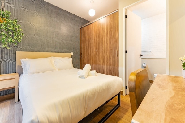 Relax in a cozy retreat with a neatly made bed, a nightstand, and a small table.