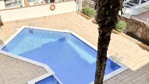 A rectangular swimming pool with a tiled deck, a palm tree in the foreground, and a lifebuoy on the wall. - CENTRIC APARTMENT with POOL in TOSSA 2 (Tossa de Mar)