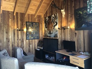 Relax in a warm and inviting space with a large flat-screen TV, comfortable seating area, and a desk for work or study.