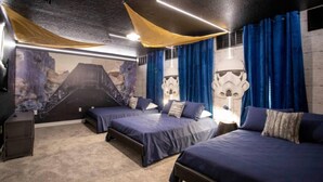 Une chambre avec trois lits, une fresque représentant un volcan et des décorations sur le thème de Star Wars.