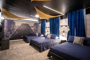 Ett rum med tre sängar, en väggmålning som föreställer en vulkan och inredning med Star Wars-tema.