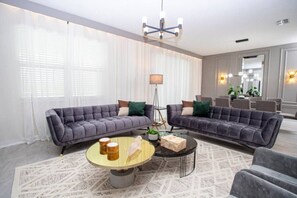 Ein modernes Wohnzimmer mit zwei grauen Sofas, einem runden Couchtisch und einer Stehlampe.