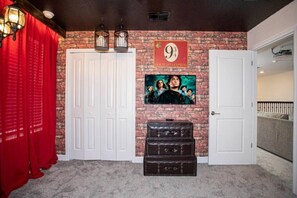 Ein Zimmer mit einer Ziegelwand, einem flachbildfernseher, der über einer dunkelholzigen Kommode angebracht ist, und einer weißen Tür auf der rechten Seite.