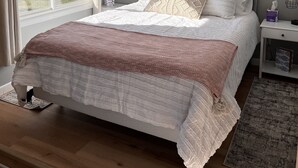 Un dormitorio con una cama grande, una ventana con vista a un lago, una mesita de noche con una lámpara y un cuadro enmarcado en la pared.