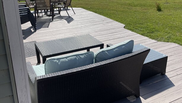Terraza con mobiliario de mimbre y vista a un lago.