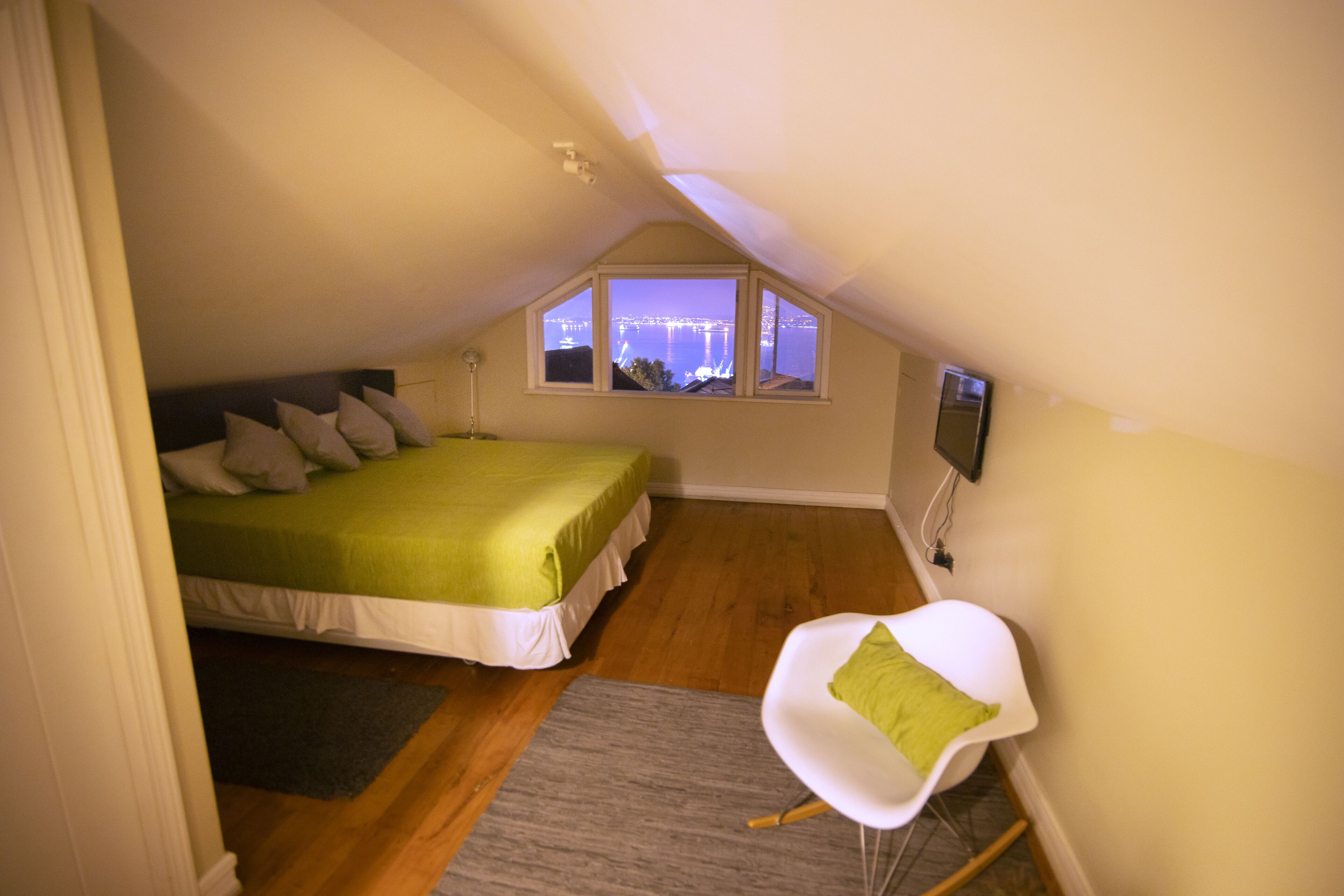 Une chambre avec un lit, une chaise, une fenêtre donnant sur un beau paysage et un téléviseur fixé au mur.