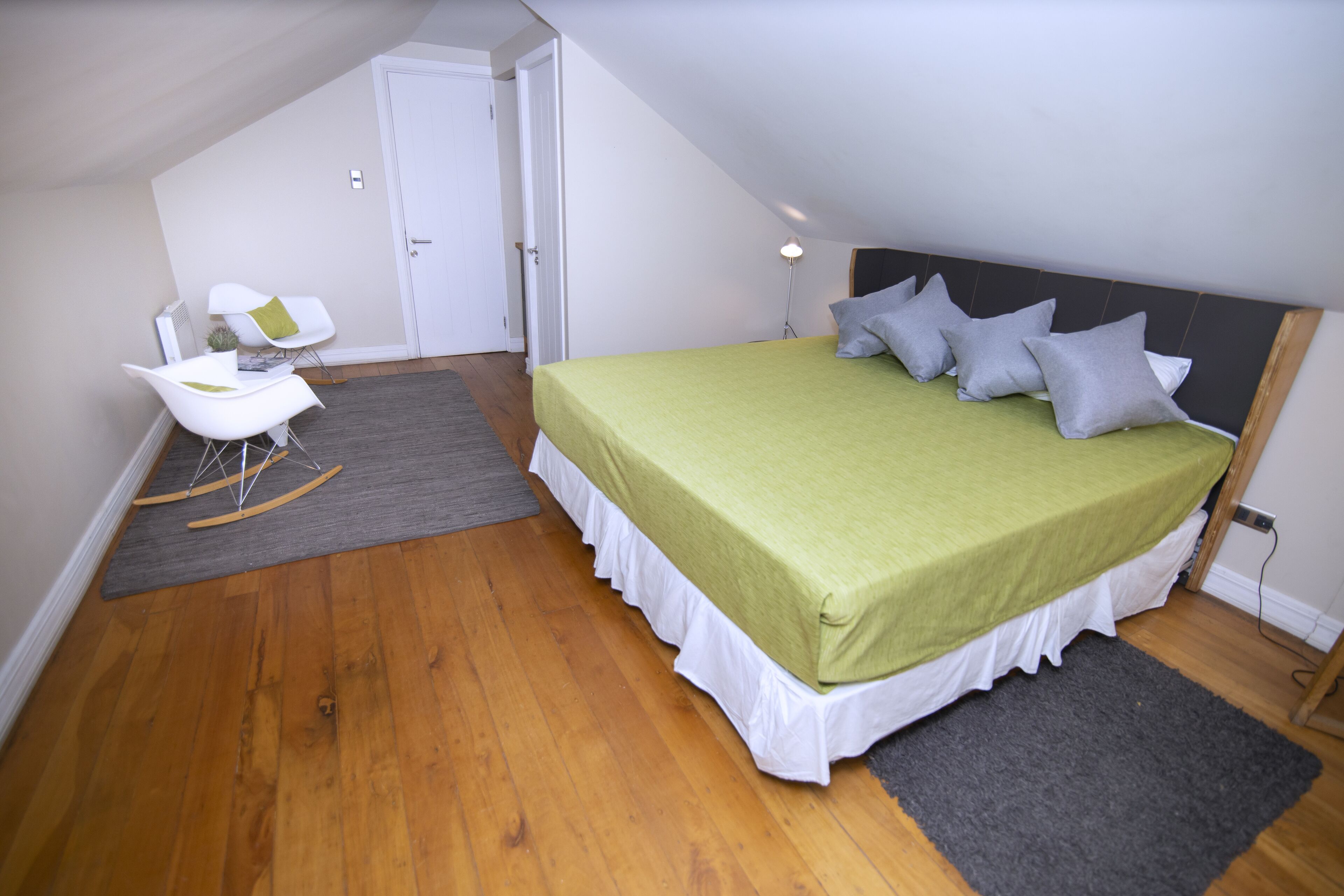 A bedroom with a bed, a rocking chair, and a desk.