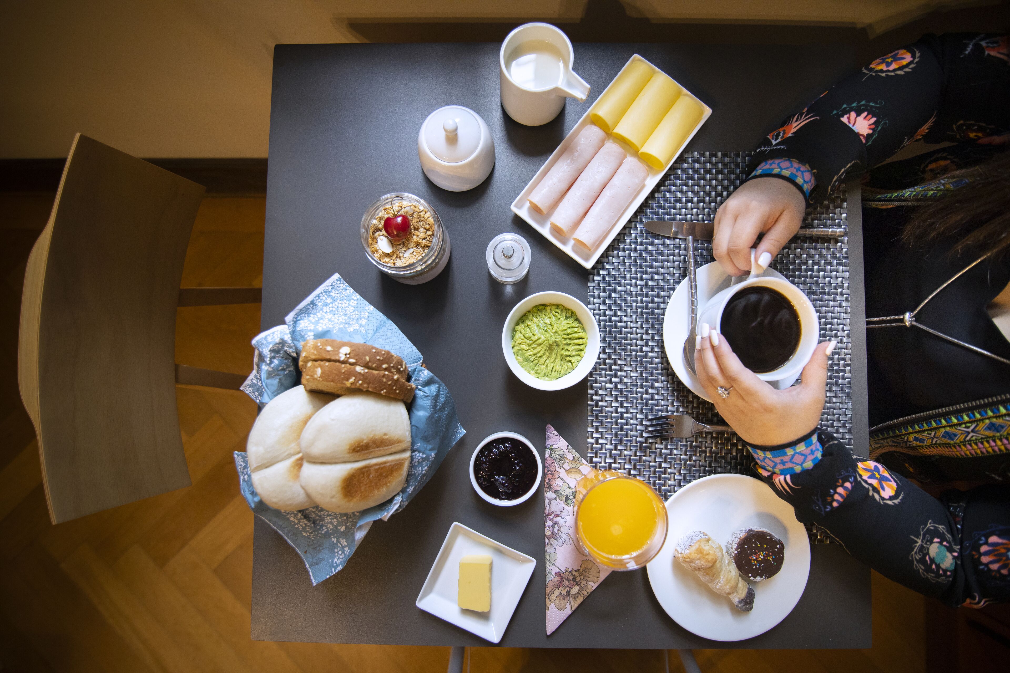 A breakfast table with various food items and a cup of coffee.