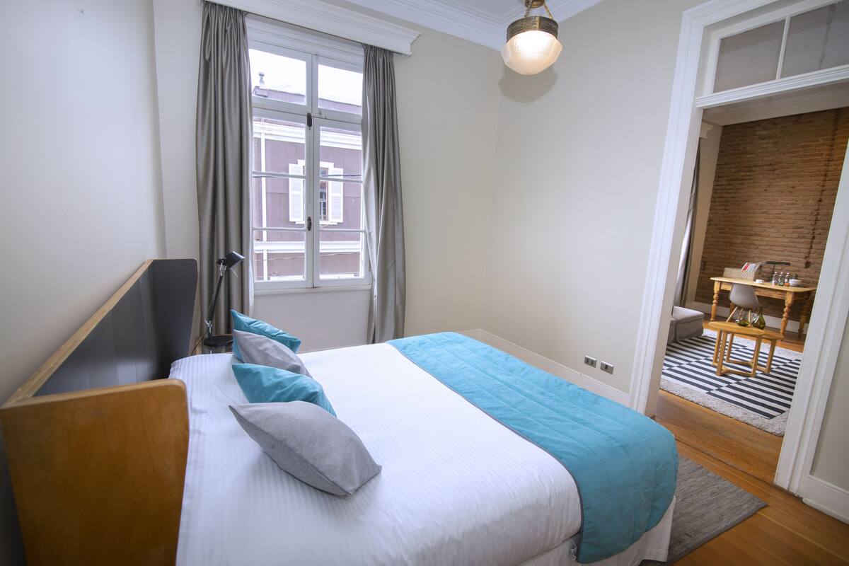Un dormitorio con cama, escritorio y vistas al exterior.