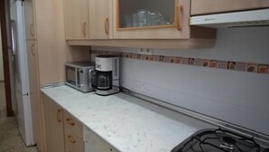 A kitchen with wooden cabinets, a microwave, a coffee maker, and a gas stove. - Casa Rural Dehesa de Algar (Algar)