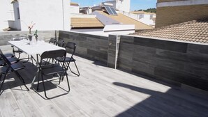 A rooftop patio with a table and chairs, a tiled floor, and a view of neighboring buildings. - Casa Rural Dehesa de Algar (Algar)
