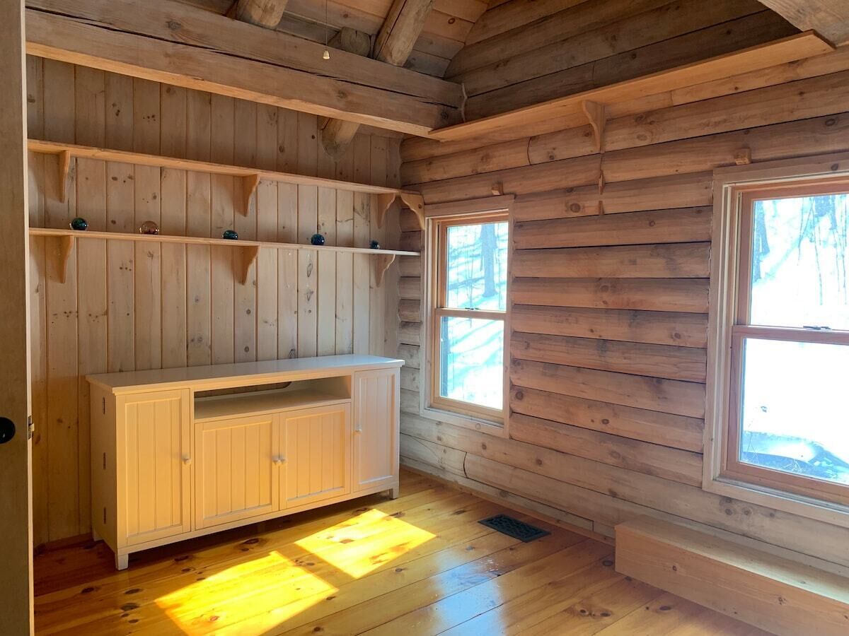 Een houten cabinemeubilair met een witte kast, houten planken en grote ramen.