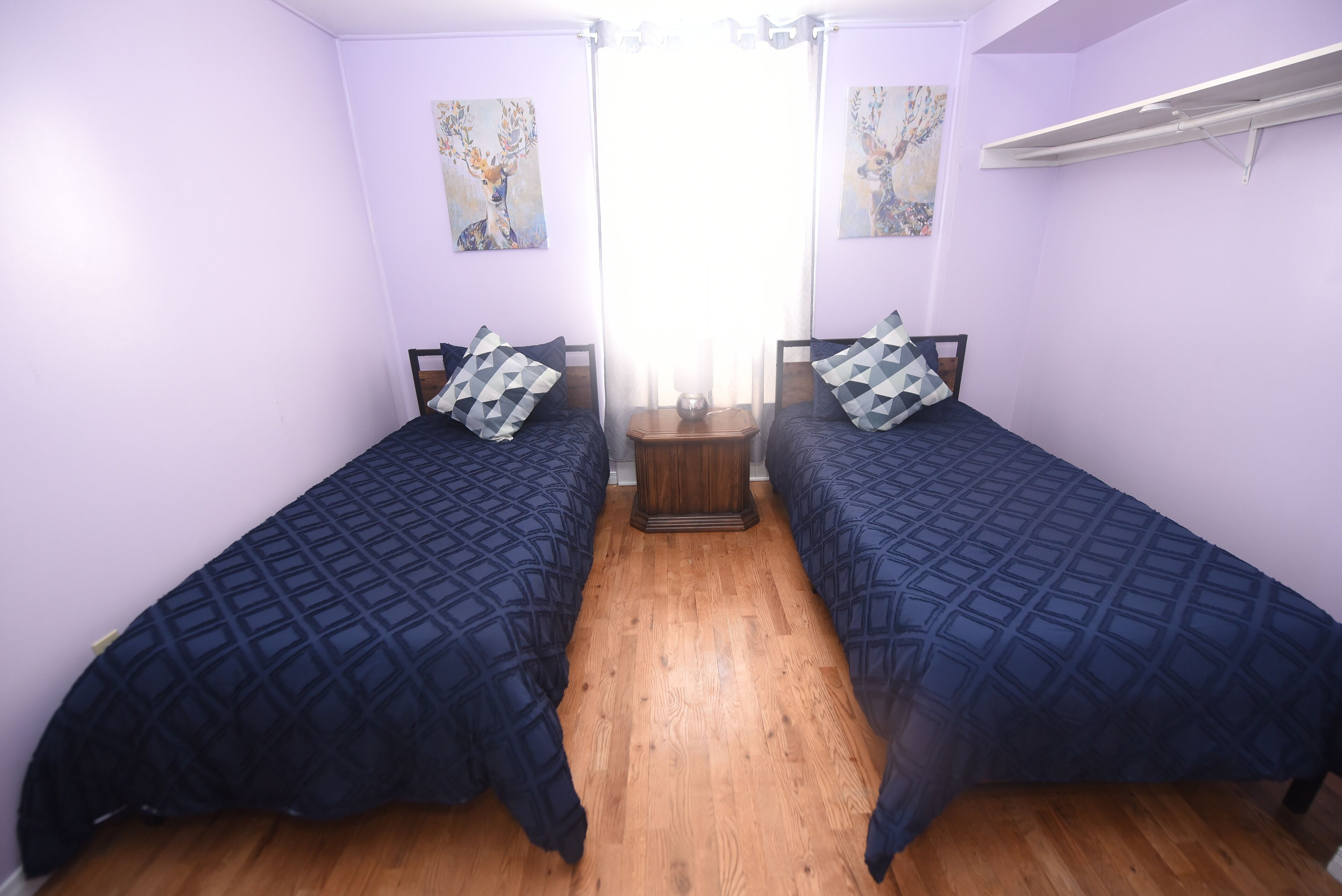 A room with two beds, wooden flooring, and artwork on the walls.