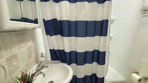 A bathroom with a white sink, a mirror, a blue and white striped shower curtain, and a white toilet. - Prime Location Duo Nest & Rest (Kingston)