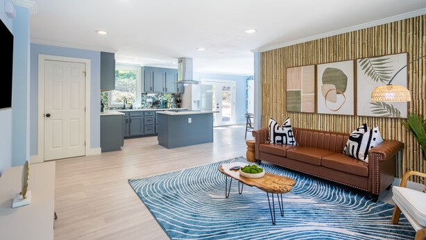 A modern living room with a brown leather sofa, a blue patterned rug, and a kitchen in the background. - Spacious Getaway 15 mins from Downtown Atlanta (Decatur)