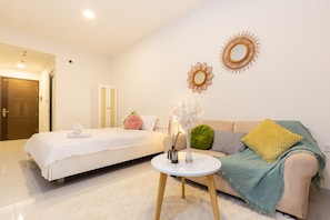 A modern hotel room with a bed, a sofa, a round table, and decorative wall art. - An Corner Soho cute Studio for couple District 1 (Ho Chi Minh City)