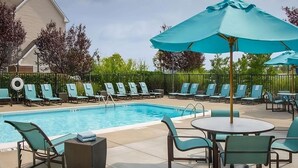 A pool area with lounge chairs and umbrellas, surrounded by a fence and greenery. - Modern Convenience Meets Comfort in Charleston! Pool, Pets are Allowed Here (Charleston)