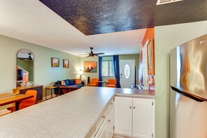 A kitchen with a central island, white cabinets, and a stainless steel refrigerator.