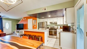 A modern kitchen with white cabinets, a large island, and a built-in oven.