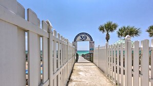 A pathway leading to a beach entrance with a sign reading "39" and palm trees on the right.