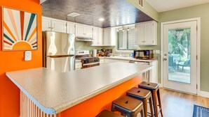 A kitchen with white cabinets, a large island, and a view through a glass door.