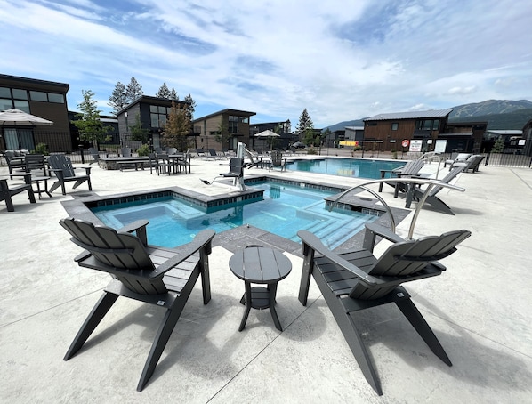 Relax by the pool with lounge chairs and a table, surrounded by breathtaking mountain views.