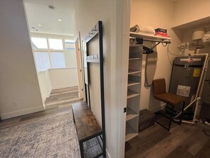 A hallway with a wooden bench, a wall-mounted shelf, and a radiator.