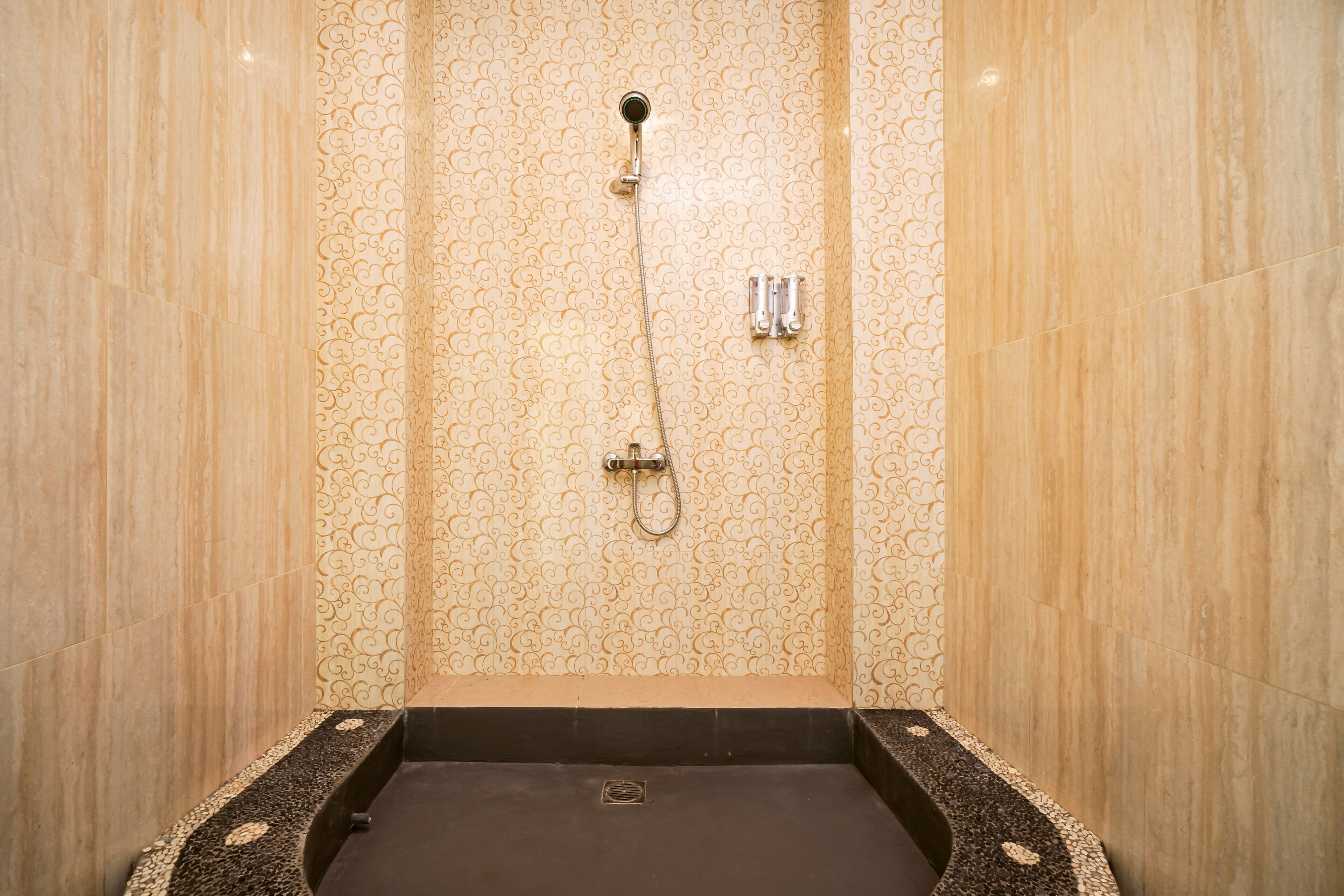 A shower with a wall-mounted faucet and a handheld showerhead.