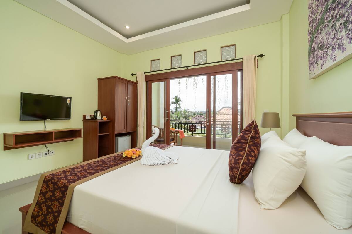 A hotel room with a bed, a television, a wardrobe, and a balcony with a view.